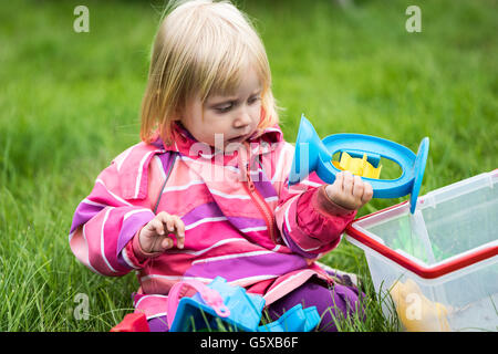 Petite fille jouant avec ses jouets dans le jardin Banque D'Images