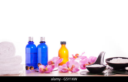 L'heure du bain se détendre ensemble de produits de beauté. Huile de massage, sel de mer et de serviette blanche sur la table en bois isolé sur fond blanc. Banque D'Images