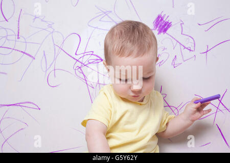 Baby Boy dessin avec crayon de cire sur le mur de plâtre Banque D'Images