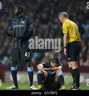 Jack Rodwell (au centre) de Manchester City parle avec l'arbitre Mike Dean (à droite) alors qu'il est blessé sur le terrain, tandis que son coéquipier Yaya Toure (à gauche) regarde Banque D'Images