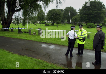 La police se tient près d'une section du cimetière Riddrie à Glasgow, où une fouille devrait reprendre après la disparition d'un jeune de 18 ans pendant les inondations. On craint que l'adolescent soit tombé dans un trou inondé de 15 pieds. Banque D'Images