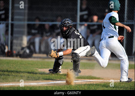 Notation Runner debout comme il bat le throw accueil à la catcher lors d'un match de l'école secondaire. USA. Banque D'Images