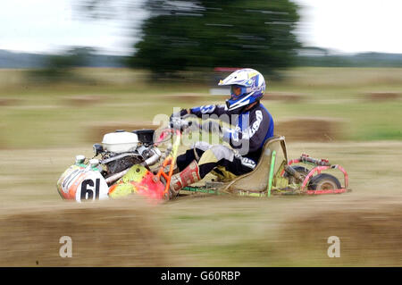 Casques de tricherie de l'équipe concurrente (61) sur une tondeuse Atco en pratique pour la course de 12 heures de la British Lawn Mower Racing Association à Pulborough, West Sussex.L'événement annuel est en cours depuis 1978.*... et il existe trois classes différentes pour différents types de tondeuses.Certaines machines de tonte modifiées peuvent atteindre 40 mph.Les équipes, chacune avec trois pilotes, traversent la nuit sur un terrain boueux pour tenter de suivre les traces de la légende du Grand Prix Sir Stirling Moss, qui a remporté la première épreuve de tonte avec le héros du Mans Derek Warwick. Banque D'Images