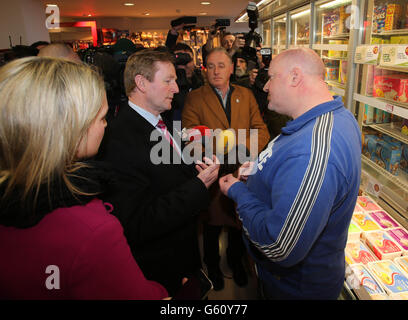 Taoiseach Enda Kenny parle avec un Garda hors service (nom non donné) dans un supermarché à Ratoath comme il rejoint le candidat de Fine Gael Helen McEntee (à gauche) sur la piste de campagne à l'élection partielle Meath East. Banque D'Images