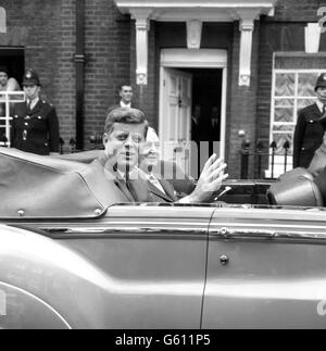 Le président américain John Kennedy déchaîne alors qu'il quitte à bord d'une voiture ouverte la résidence de sa belle-sœur de Buckingham Palace pour l'ambassade des États-Unis. Banque D'Images