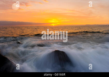 Ocean sunset est une pièce lumineuse avec un paysage marin d'or gentle wave rouler à la rive. Banque D'Images