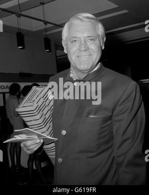 Cary Grant, 68 ans, acteur de cinéma hollywoodien aux cheveux argentés, quitte Heathrow pour un vol à destination de New York. Banque D'Images