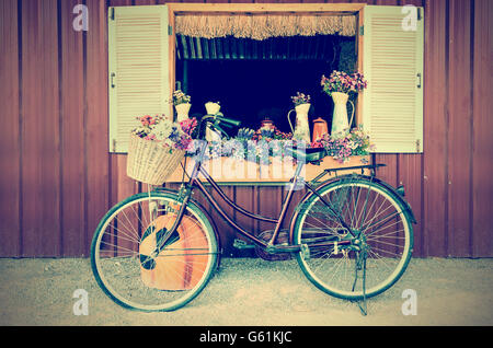 Vieux vélo et fleurs stationné près de la fenêtre ferme à campagne dans un style vintage Banque D'Images