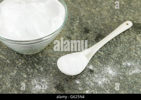 Bicarbonate de soude dans un bol et une cuillère de soda sur table en pierre Banque D'Images