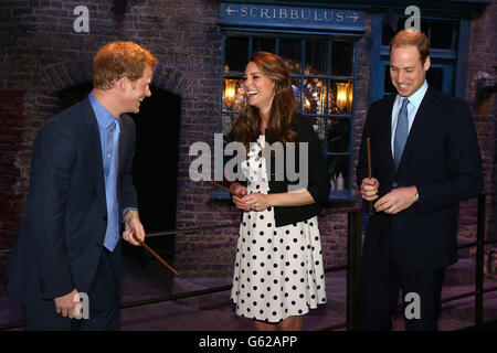 Le prince Harry, avec le duc et la duchesse de Cambridge, rient alors qu'ils tiennent des baguettes sur le set utilisé pour représenter Diagon Alley dans Harry Potter films lors de leur visite aux studios Warner Bros de Leavesden, Herts où les films populaires ont été produits. Banque D'Images