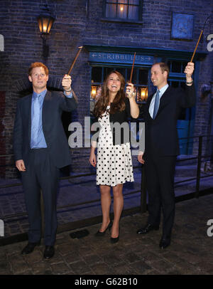 Le prince Harry, la duchesse et le duc de Cambridge avec leurs baguettes sur le set utilisé pour représenter Diagon Alley dans les films Harry Potter lors de leur visite aux studios Warner Bros de Leavesden, Herts où les films populaires ont été produits. Banque D'Images