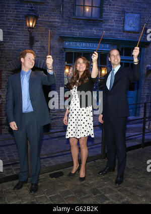 Le prince Harry, la duchesse et le duc de Cambridge avec leurs baguettes sur le set utilisé pour représenter Diagon Alley dans les films Harry Potter lors de leur visite aux studios Warner Bros de Leavesden, Herts où les films populaires ont été produits. Banque D'Images