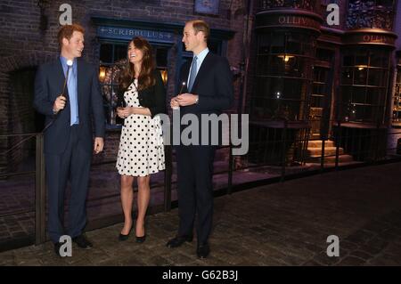 Le prince Harry, la duchesse et le duc de Cambridge avec leurs baguettes sur le set utilisé pour représenter Diagon Alley dans les films Harry Potter lors de leur visite aux studios Warner Bros de Leavesden, Herts où les films populaires ont été produits. Banque D'Images