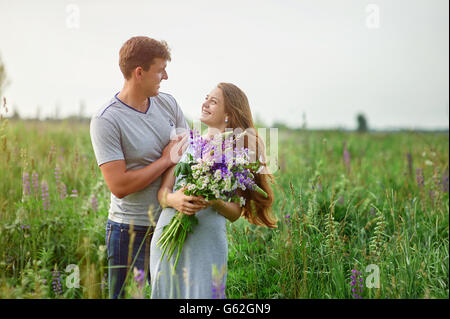 Couple heureux de jouer les uns avec les autres dans un champ bouquet de lupins Banque D'Images