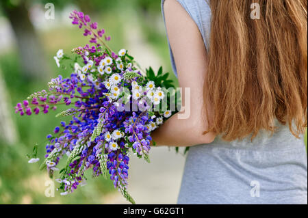 Femme tenant un bouquet de fleurs de lupin bleu Banque D'Images