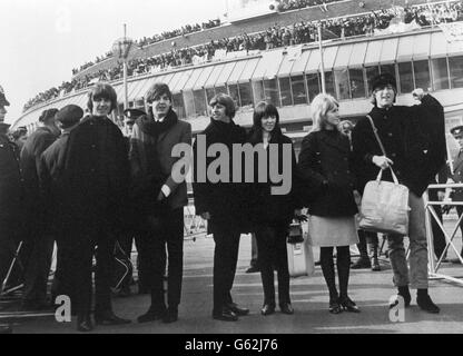 Plus de 2,000 adolescents dans les galeries d'observation crient leurs puits de farewell aux Beatles, vus à l'aéroport de Londres lorsqu'ils sont partis pour l'Autriche pour poursuivre les travaux de localisation sur leur deuxième film. (De gauche à droite) George Harrison, Paul McCartney, Ringo Starr avec sa mariée Maureen et John Lennon avec sa femme Cynthia. Banque D'Images