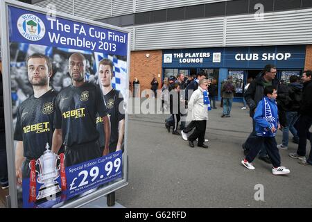 Football - Barclays Premier League - Wigan Athletic / Tottenham Hotspur - DW Stadium.Les fans de Wigan Athletic marchent devant un panneau publicitaire édition spéciale FA Cup final replica shirts, à l'extérieur du sol Banque D'Images