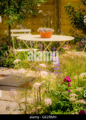 Table et chaises à l'extérieur sur terrasse avec fleurs en premier plan et en arrière-plan de clôture Banque D'Images