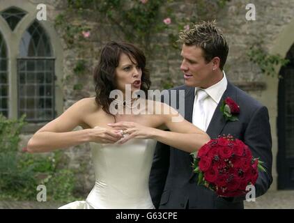 La rameuse olympique James Cracknell tient le bouquet de sa femme Beverley Turner alors qu'elle remplace son anneau d'engagement au bout de son doigt après leur mariage au château de Clearwell à Gloucestershire. Banque D'Images