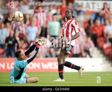 Clayton Donaldson de Brentford observe que Wes Foderingham, gardien de but de Swindon Town, ne parvient pas à arrêter son tir et il obtient ses équipes le troisième but du jeu Banque D'Images