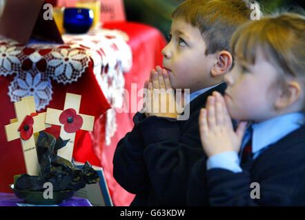 Jonah Rzeskiewicz et Lauren Smythe, quatre ans, prient pour la paix lors d'une assemblée spéciale pour marquer le jour de l'armistice, à l'école de St Vincent à Altrincham, Cheshire. Banque D'Images