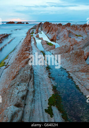 Côte de l'océan crépuscule avec formations de roches stratiformes striée (Océan Atlantique, Cantabria, Espagne). Banque D'Images