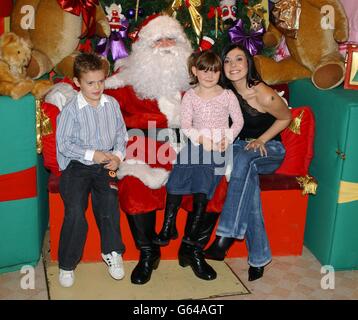 La chanteuse Kym Marsh, avec ses enfants David et Emily assis avec le Père Noël dans la grotte de Santa au centre commercial Lakeside, Thurrock après avoir allumé les lumières de Noël. Banque D'Images