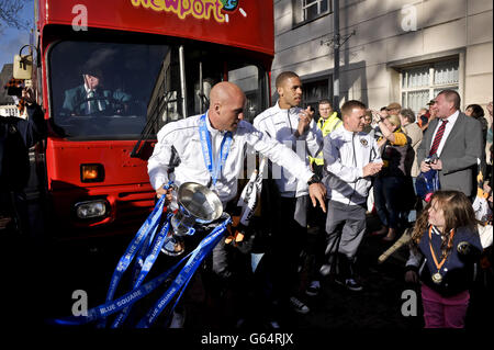 Les joueurs de l'équipe de football AFC de Newport County débarquent du bus à toit ouvert, y compris le capitaine de l'équipe David Pipe tenant le trophée, au centre civique pendant le défilé de victoire des clubs à travers Newport. Banque D'Images