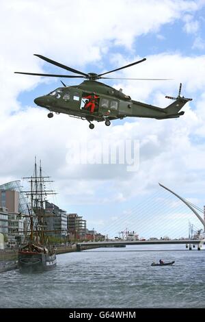 Un corps d'aviation irlandais Agusta Westland AW139 survole la rivière Liffey à Dublin, avec la réplique du navire de famine le Jeannie Johnston en arrière-plan, pendant un photocall pour Flightfest 2013 qui voit des dizaines d'avions voler au-dessus du centre-ville. Banque D'Images