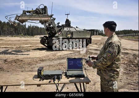 Un soldat utilise un contrôleur de type consol pour contrôler un excaveur blindé Terrier, qui est contrôlé par télécommande lors d'un dévoilement au Centre des véhicules blindés de la Défense, Bovington, Dorset. Banque D'Images