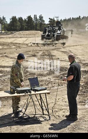 Un ingénieur utilise un contrôleur de type console de jeux pour contrôler un excaveur blindé Terrier, qui est contrôlé par télécommande lors d'un dévoilement au Centre des véhicules blindés de défense, Bovington, Dorset. Banque D'Images