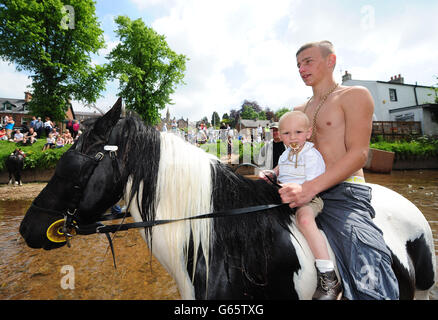 Jeff Nesham, David Briganti de 16 et 18 mois, de Gateshead, montez à bord de leur cheval dans l'Eden River à la foire du cheval Appleby, le rassemblement annuel de gitans et de voyageurs à Appleby, Cumbria. Banque D'Images