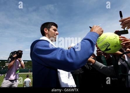 La Serbie Novak Djokovic signe des autographes après une séance d'entraînement au cours du sixième jour des Championnats de Wimbledon au All England Lawn tennis and Croquet Club, Wimbledon. Banque D'Images