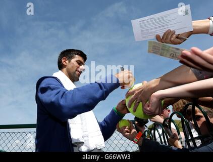 La Serbie Novak Djokovic signe des autographes après une séance d'entraînement au cours du sixième jour des Championnats de Wimbledon au All England Lawn tennis and Croquet Club, Wimbledon. Banque D'Images