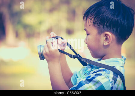 Asian boy taking photo par caméra film vintage trouble sur la nature, sur l'été dans la journée. Enfant dans la nature, à l'extérieur Banque D'Images