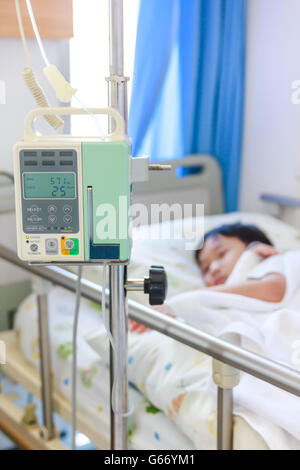 Asie maladie garçon couché sur lit de malade à l'hôpital avec une pompe à perfusion perfusion IV intraveineuse. Profondeur de champ. Banque D'Images