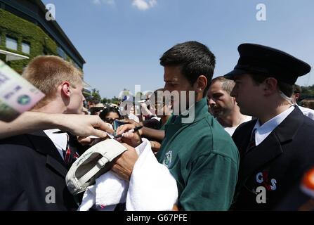 La Serbie Novak Djokovic signe des autographes après une séance d'entraînement au cours du douze jour des Championnats de Wimbledon au All England Lawn tennis and Croquet Club, Wimbledon. Banque D'Images