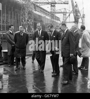 Le prince Philip, duc d'Édimbourg, en visite au nouveau navire géant Cunard Q4, est présenté aujourd'hui autour du chantier naval de John Brown, Clydebank, en Écosse, par Lord Aberconway, président de John Brown (au centre), avec M. John Rannie, directeur général de John Brown (à droite). Le duc visitait le chantier naval pour sa première vue du Q4, que la Reine doit nommer et lancer le 20 septembre. Banque D'Images