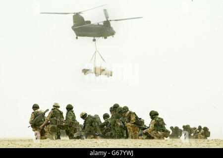 Les soldats britanniques du 51e régiment Sqn de la Royal Air Force observent un Chinook de la force d'hélicoptère conjointe de la RAF lorsqu'il lève un véhicule Land Rover et sa remorque lors d'une opération d'assaut aérien d'entraînement visant à capturer un aérodrome ennemi, dans le désert à l'extérieur de la ville de Koweït. 07/04/2004: Un marché "assidûment bâclée" a laissé la RAF avec huit hélicoptères Chinook d'une valeur de 259 millions, qu'elle ne peut pas utiliser, il a été révélé mercredi 7 avril 2004. Les inquiétudes au sujet du logiciel de cockpit signifient que l'engin ne peut pas être utilisé par temps nuageux, a déclaré un rapport de l'organisme de surveillance des dépenses de Westminster, The National Audit Banque D'Images