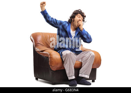 Portrait d'un gars endormi assis sur un fauteuil bâillement isolé sur fond blanc Banque D'Images