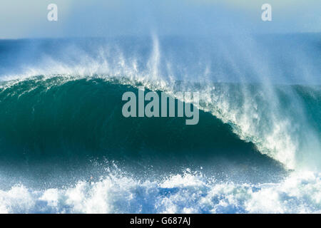 Gros plan des vagues d'océan s'écraser creux de mur d'eau le long du littoral de la plage bleue. Banque D'Images