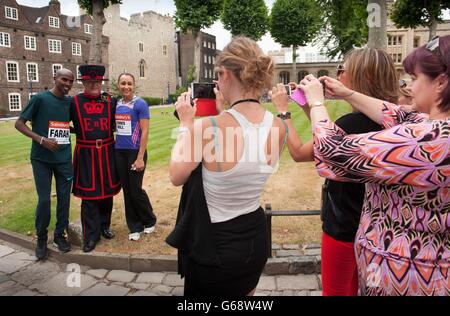 Les champions olympiques Mo Farah et Jessica Ennis-Hill posent pour des photos avec Yeoman Warder James Duncan tandis que les gens prennent des photos pendant la séance photo à la Tour de Londres, Londres. Banque D'Images