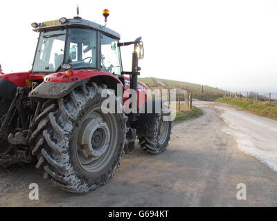 Sale énorme tracteur agricole rouge couvert de craie blanche du sol North Wessex Downs stationnée sur le promeneur à pied sur Walbury Hill. Banque D'Images