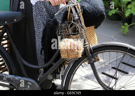 Femme avec panier plein d'œufs frais hen livré sur un vieux vélo rouillé Banque D'Images