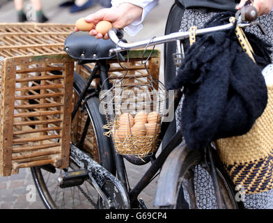 Femme âgée sur vélo avec deux œufs dans la main et beaucoup d'oeufs de poule dans le panier Banque D'Images