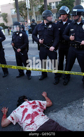 Un militant de la paix couvert de faux sang se trouve aux pieds de la police lors d'une manifestation à Hollywood. La police de Los Angeles a empêché les manifestants anti-guerre en Irak d'atteindre le Kodak Theatre où les 75e Academy Awards sont présentés. Banque D'Images