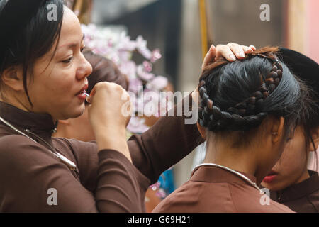 Femme en ao Dai prépare les filles pour la cérémonie religieuse au centre du Vietnam Banque D'Images