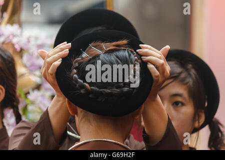 Femme en ao Dai prépare les filles pour la cérémonie religieuse au centre du Vietnam Banque D'Images