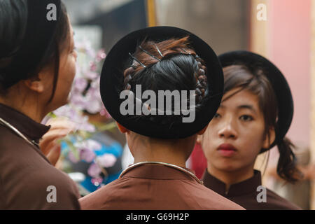 Femme en ao Dai prépare les filles pour la cérémonie religieuse au centre du Vietnam Banque D'Images