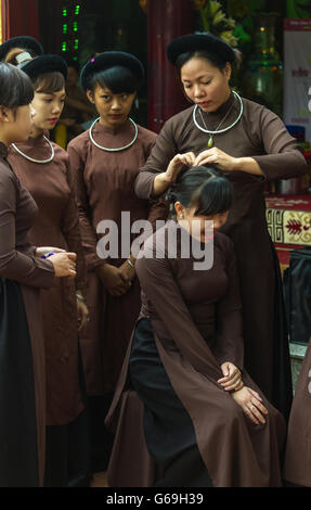 Femme en ao Dai prépare les filles pour la cérémonie religieuse au centre du Vietnam Banque D'Images